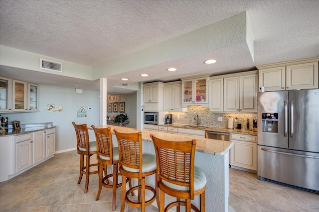 kitchen featuring sink, a breakfast bar, appliances with stainless steel finishes, and light stone countertops