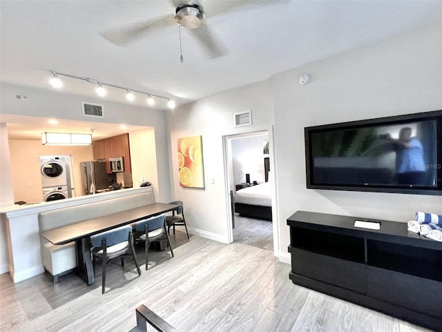 living room with light wood-type flooring, ceiling fan, and stacked washer / drying machine