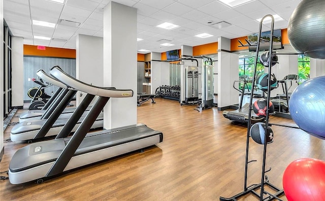 gym with a paneled ceiling and light wood-type flooring