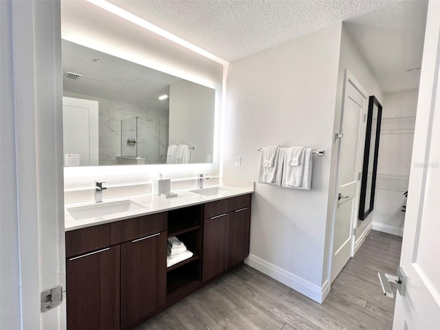 bathroom featuring hardwood / wood-style flooring, vanity, a shower with door, and a textured ceiling