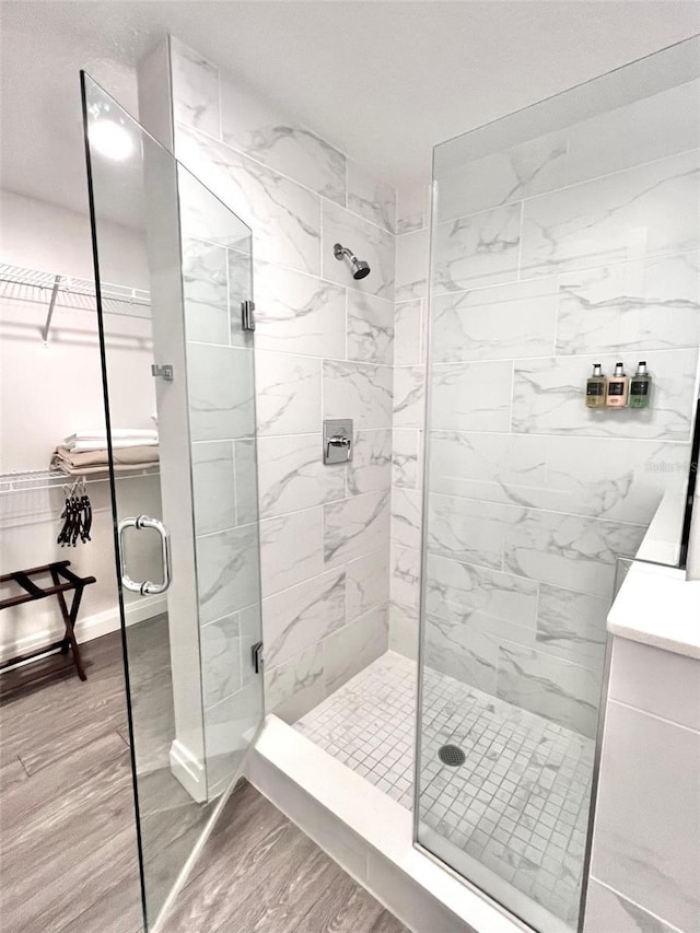 bathroom with wood-type flooring and a shower with shower door