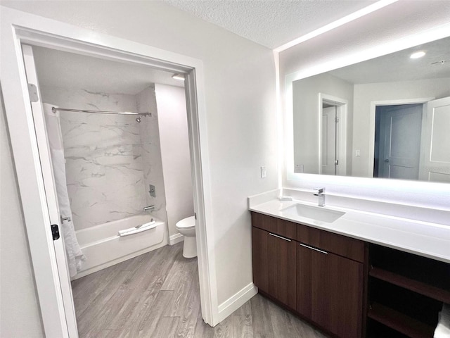 full bathroom featuring wood-type flooring, a textured ceiling, toilet, vanity, and tiled shower / bath