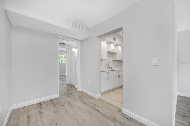 hallway with sink and light hardwood / wood-style flooring