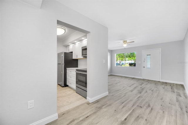 kitchen with ceiling fan, white cabinets, stainless steel appliances, and light hardwood / wood-style flooring