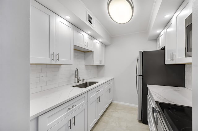 kitchen with white cabinetry, stainless steel appliances, decorative backsplash, sink, and light stone counters