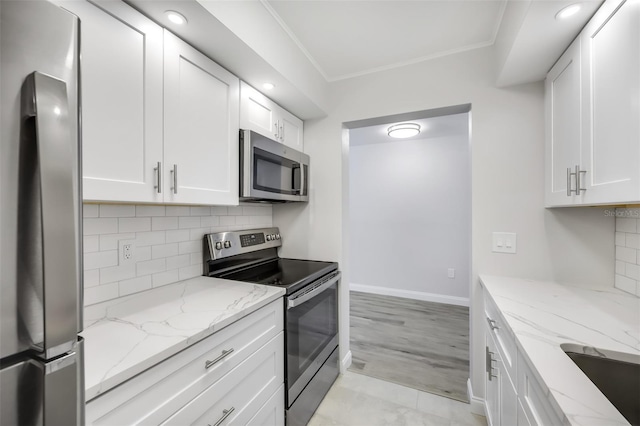 kitchen featuring stainless steel appliances, ornamental molding, white cabinets, and light stone countertops