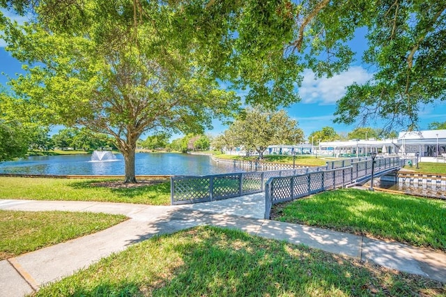 surrounding community featuring a water view and a lawn