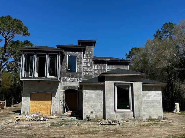 view of front of property with a shingled roof and concrete block siding