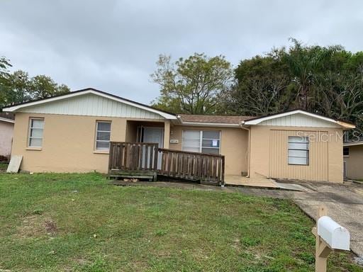 rear view of property featuring a wooden deck and a lawn