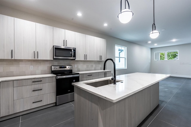 kitchen featuring a kitchen island with sink, decorative light fixtures, backsplash, stainless steel appliances, and sink