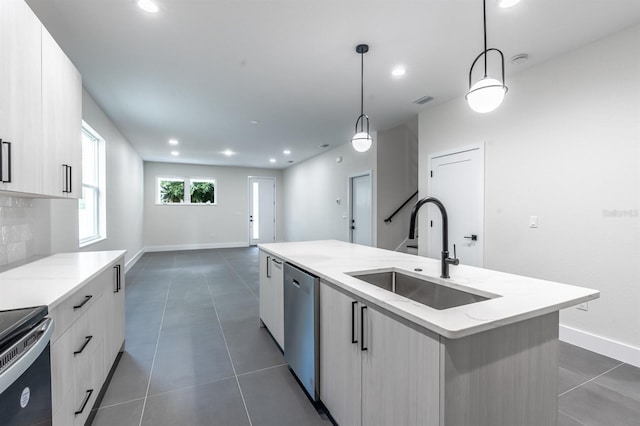 kitchen with dark tile floors, a kitchen island with sink, decorative light fixtures, stainless steel dishwasher, and sink