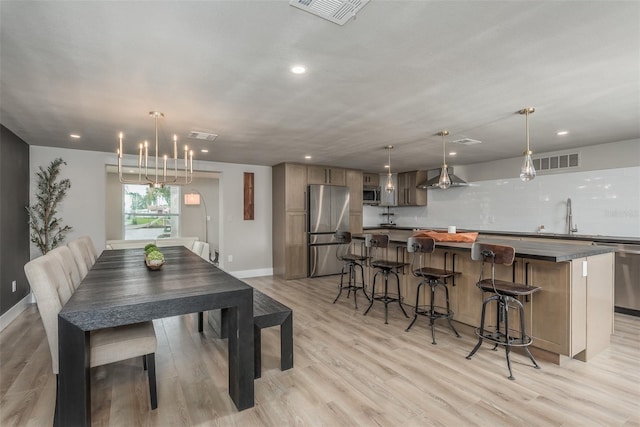 dining area featuring sink, a chandelier, and light wood-type flooring