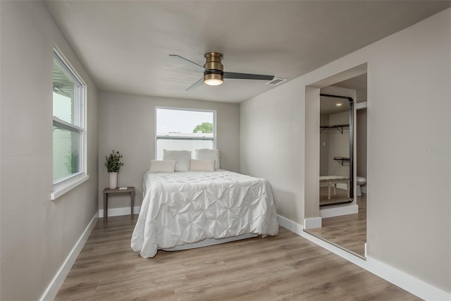 bedroom with light hardwood / wood-style flooring, a spacious closet, ceiling fan, and multiple windows