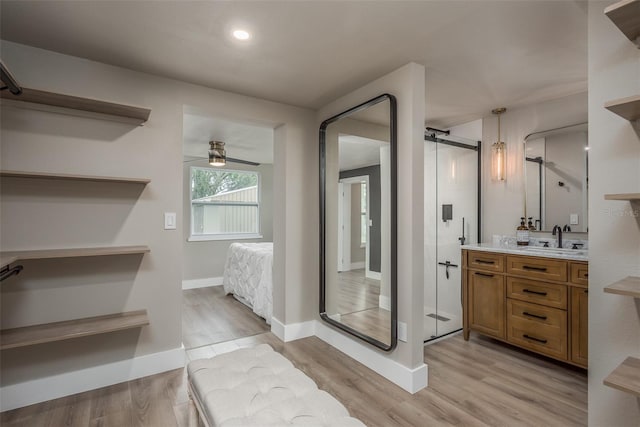 bathroom with wood-type flooring, ceiling fan, vanity, and a shower with door