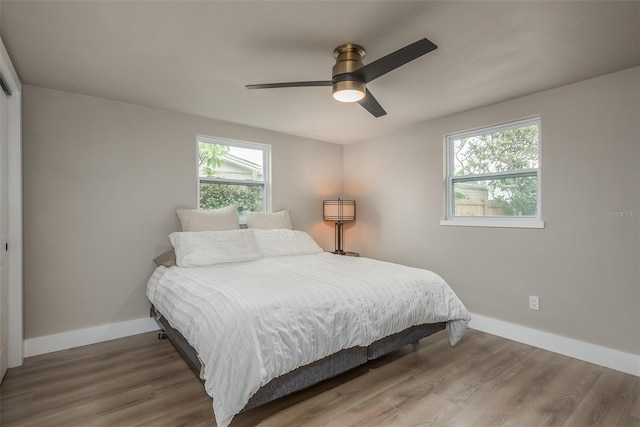 bedroom with dark hardwood / wood-style flooring, multiple windows, and ceiling fan