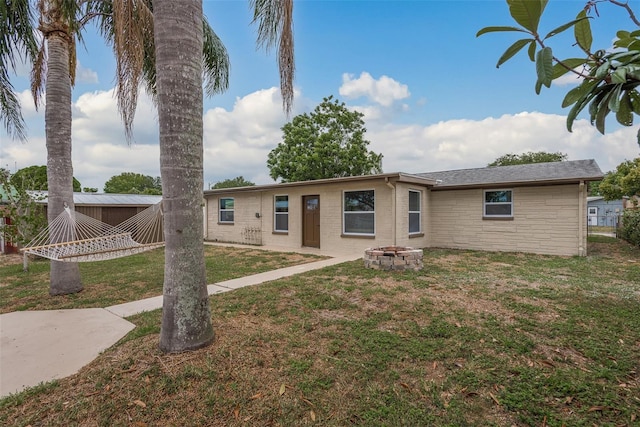 back of property with a fire pit and a lawn