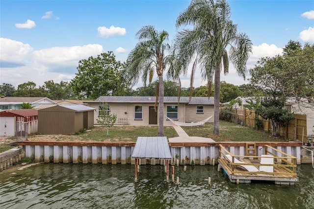 view of dock with a water view and a yard