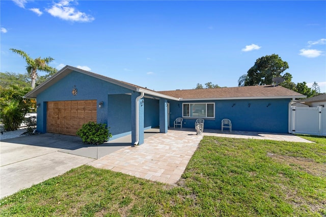 ranch-style home with a front lawn, a garage, and a patio area