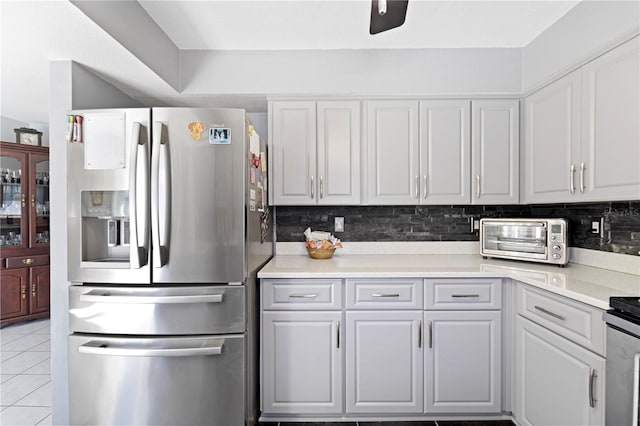 kitchen with light tile floors, white cabinets, tasteful backsplash, and stainless steel fridge