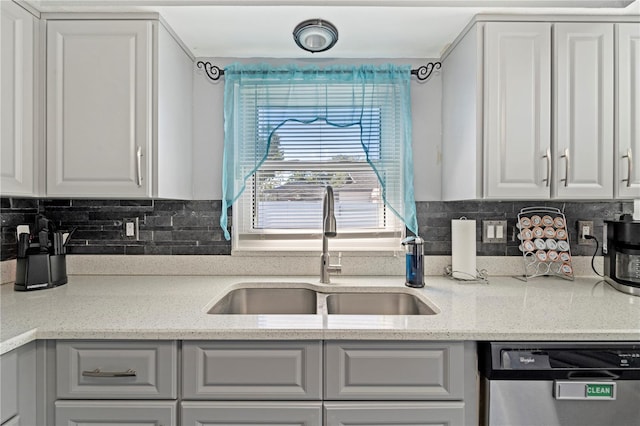 kitchen featuring tasteful backsplash, sink, light stone countertops, and dishwasher