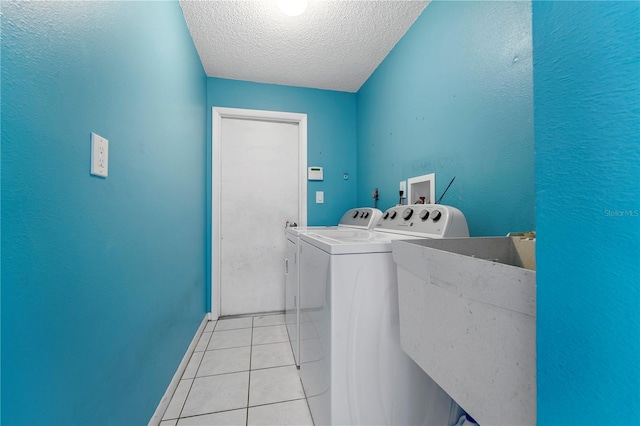 washroom featuring light tile floors, hookup for an electric dryer, a textured ceiling, hookup for a washing machine, and washing machine and dryer