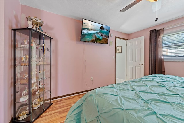 bedroom with a textured ceiling, ceiling fan, and light hardwood / wood-style flooring