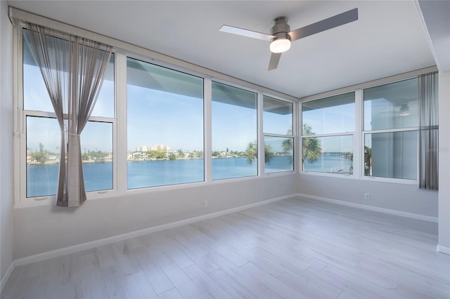 unfurnished sunroom with a water view and ceiling fan