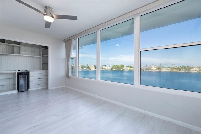 interior space featuring light hardwood / wood-style flooring, a water view, and ceiling fan