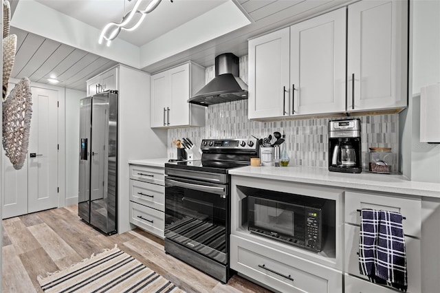 kitchen with wall chimney range hood, backsplash, white cabinets, black appliances, and light wood-type flooring