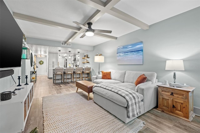 living room with ceiling fan, beam ceiling, and light hardwood / wood-style flooring