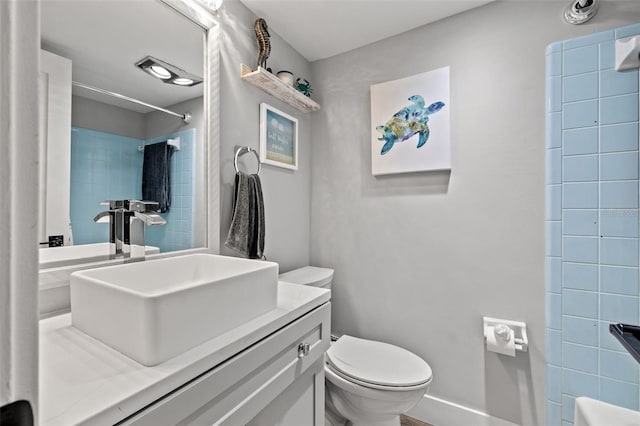 bathroom featuring tiled shower, vanity, and toilet