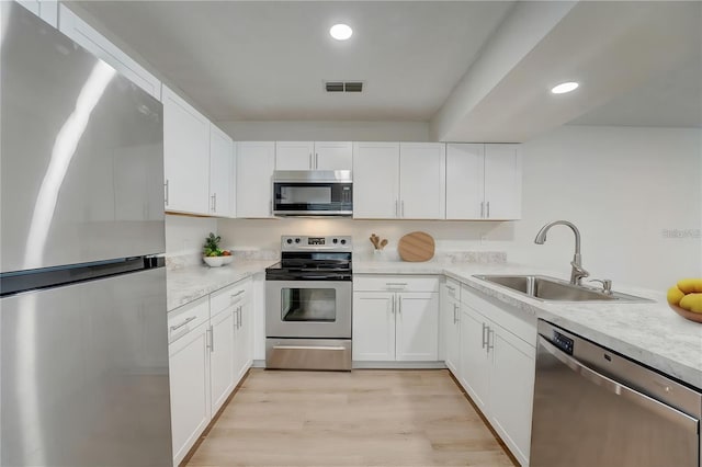 kitchen with white cabinets, light hardwood / wood-style flooring, stainless steel appliances, and sink