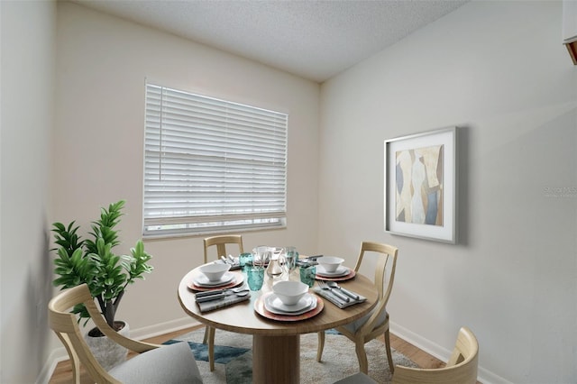 dining room with wood-type flooring and a textured ceiling