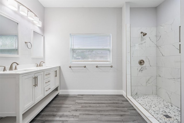 bathroom featuring wood-type flooring, plenty of natural light, a tile shower, and double sink vanity