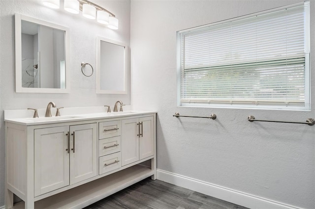 bathroom featuring wood-type flooring, plenty of natural light, double sink, and large vanity