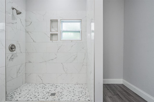 bathroom with tiled shower and hardwood / wood-style flooring