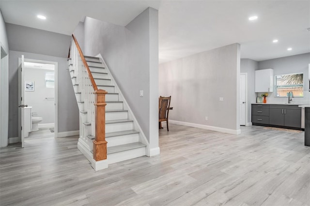 stairway with sink and light wood-type flooring