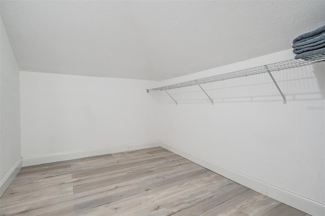 spacious closet featuring light hardwood / wood-style flooring and vaulted ceiling