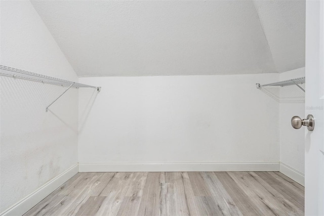 spacious closet with light hardwood / wood-style flooring and vaulted ceiling