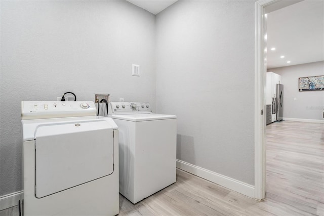 laundry area with hookup for a washing machine, light hardwood / wood-style floors, and washer and dryer