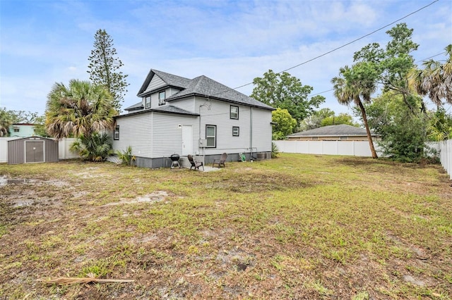 rear view of house with a storage unit and a lawn