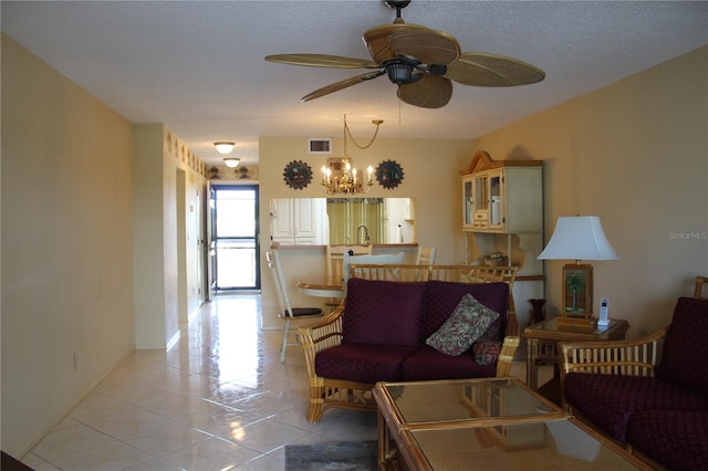 living room with ceiling fan with notable chandelier, light tile floors, and a textured ceiling