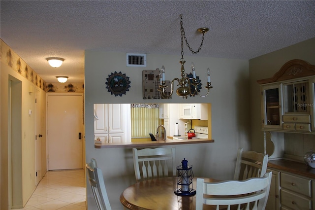 tiled dining space featuring a chandelier and a textured ceiling