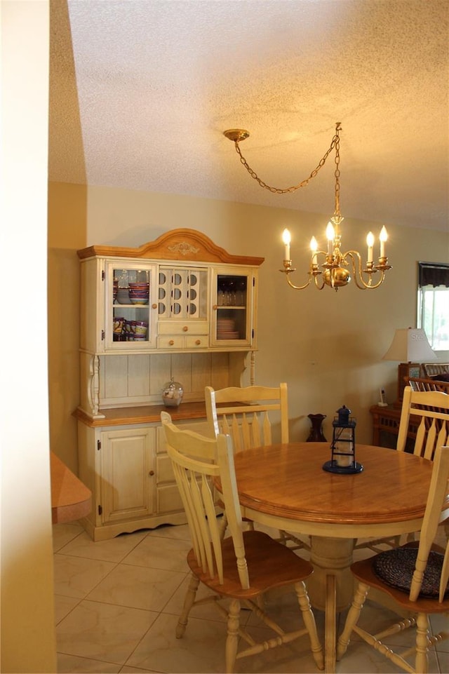 dining area with a textured ceiling, light tile floors, and an inviting chandelier