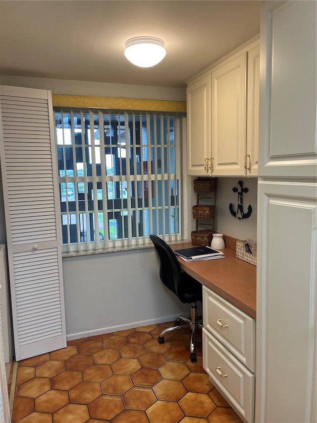 office space featuring baseboards and built in study area