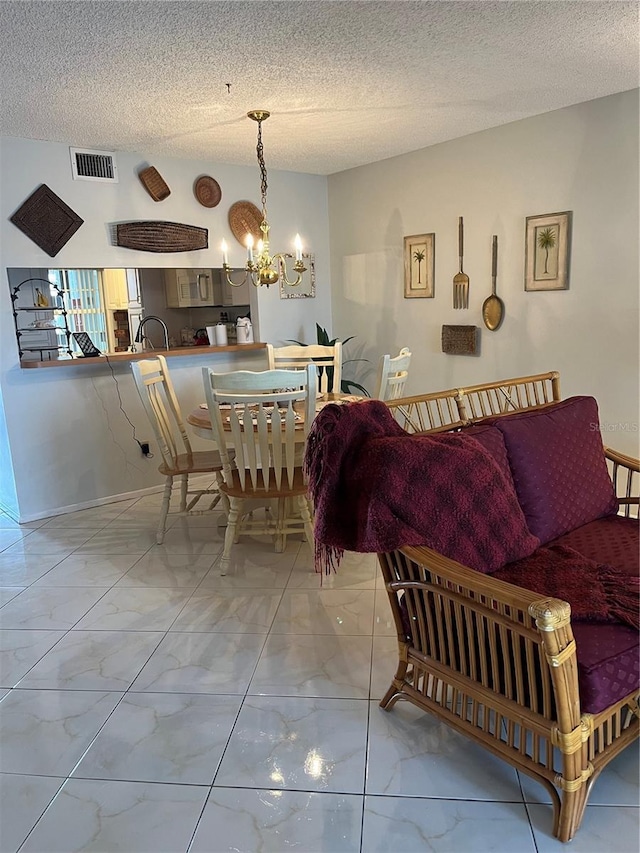 dining area featuring marble finish floor, visible vents, a textured ceiling, and an inviting chandelier