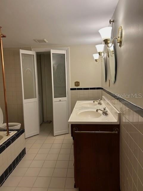 bathroom featuring vanity, tile walls, toilet, and tile patterned floors