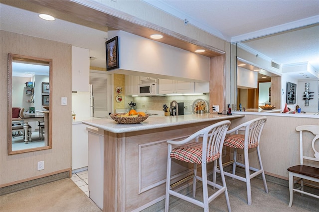 kitchen featuring light colored carpet, tasteful backsplash, a kitchen breakfast bar, and kitchen peninsula