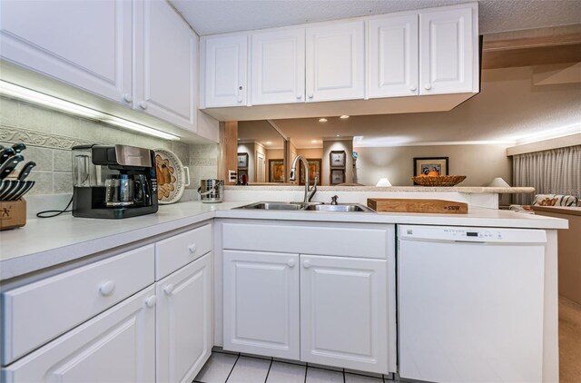 kitchen with kitchen peninsula, sink, white cabinets, white dishwasher, and tasteful backsplash