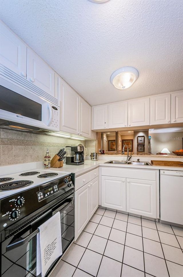 kitchen with sink, white appliances, white cabinetry, and light tile floors